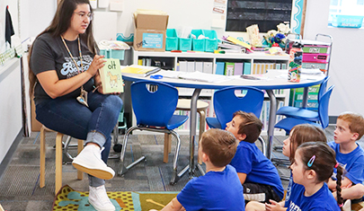 Teacher reading a book to children sitting on the classroom floor
